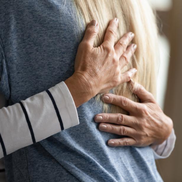 Eine Person umarmt eine andere Person mit blonden Haaren.