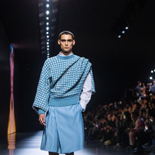 Ein Model präsentiert ein blaues Outfit auf einem Laufsteg.