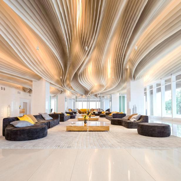 Eine Hotellobby mit geschwungenen Deckenpaneelen und modernen Möbeln.