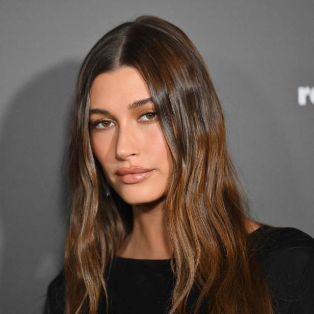 Porträt von Hailey Bieber mit braunem, gewelltem Haar.