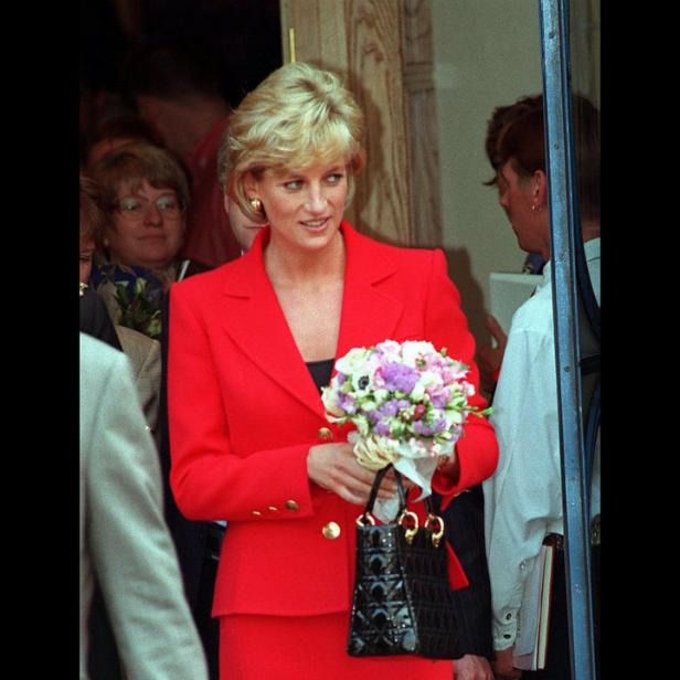 Diana, Prinzessin von Wales, in einem roten Kostüm mit Blumenstrauß und Handtasche.
