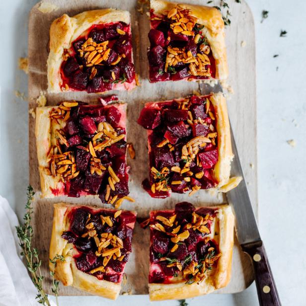 Ein auf einem Holzbrett angerichteter Rote-Bete-Kuchen mit Mandeln.