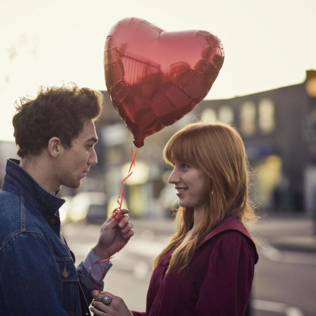 Ein junges Paar mit einem roten Herzluftballon am Valentinstag.