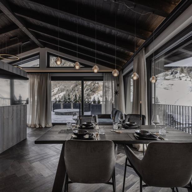 Ein Esszimmer mit gedecktem Tisch und Blick auf eine verschneite Berglandschaft.