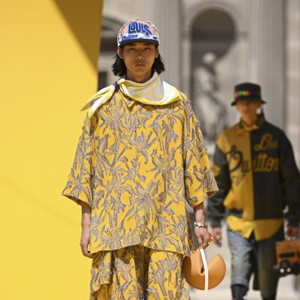 Ein Model in gelbem Outfit mit Palmenmuster auf einem Laufsteg von Louis Vuitton.