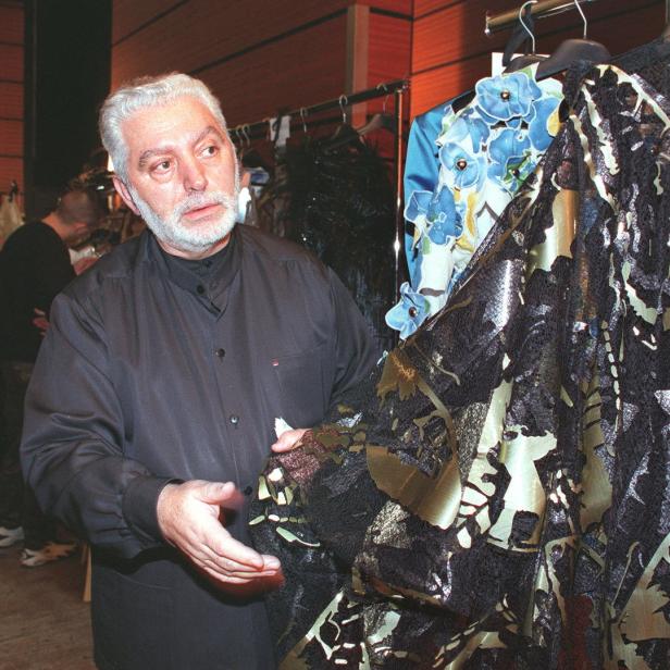 Paco Rabanne betrachtet ein Kleidungsstück mit floralem Muster.