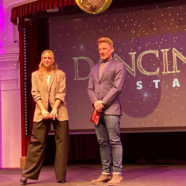 Zwei Personen stehen auf einer Bühne vor dem „Dancing Stars“-Logo.