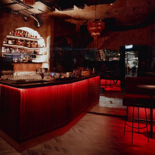 Eine Bar mit roter Beleuchtung und zwei auffälligen Kronleuchtern.