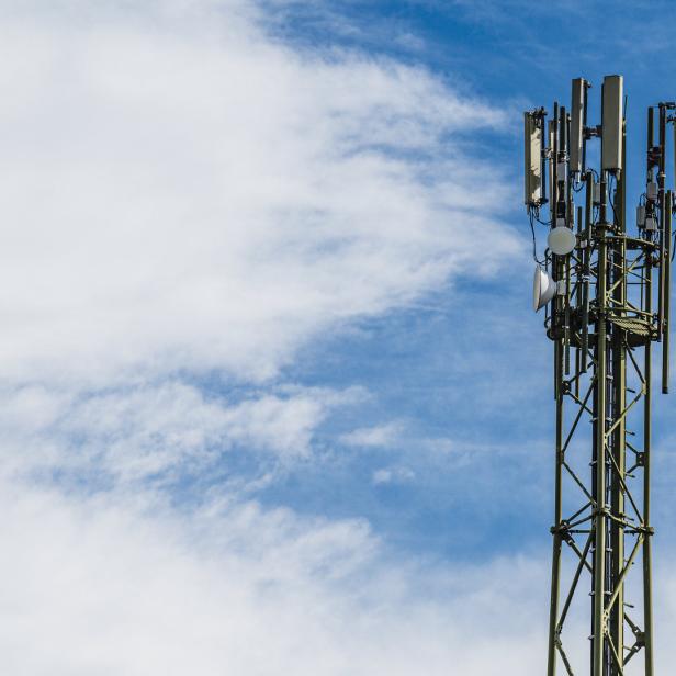Ein Mobilfunkmast steht vor einem blau-weissen Himmel.