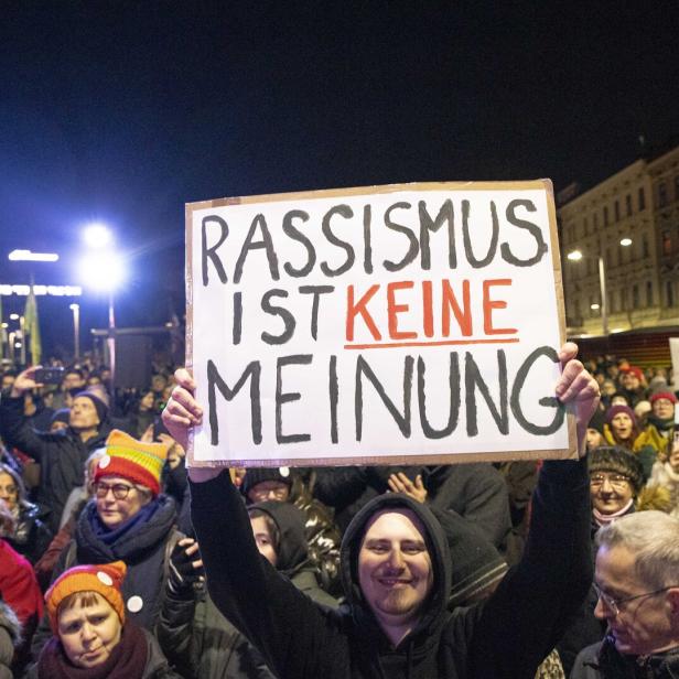 Ein Mann hält bei einer Demonstration ein Schild mit der Aufschrift „Rassismus ist keine Meinung“ hoch.