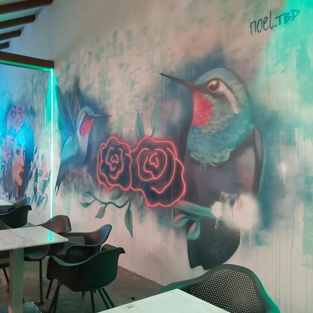 Ein Café mit Wandmalereien von Kolibris und Rosen.