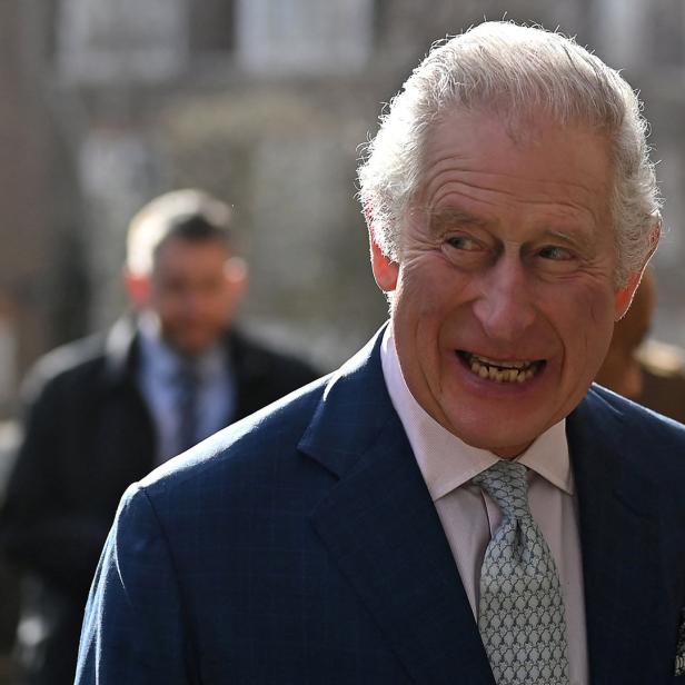 König Charles III. lächelt in einem blauen Anzug.