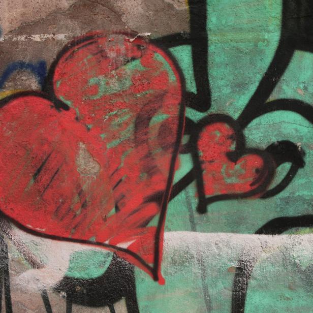 Graffiti mit zwei roten Herzen auf einer Betonwand.