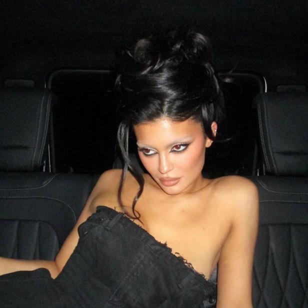 Kylie Jenner posiert in einem trägerlosen schwarzen Oberteil im Auto.