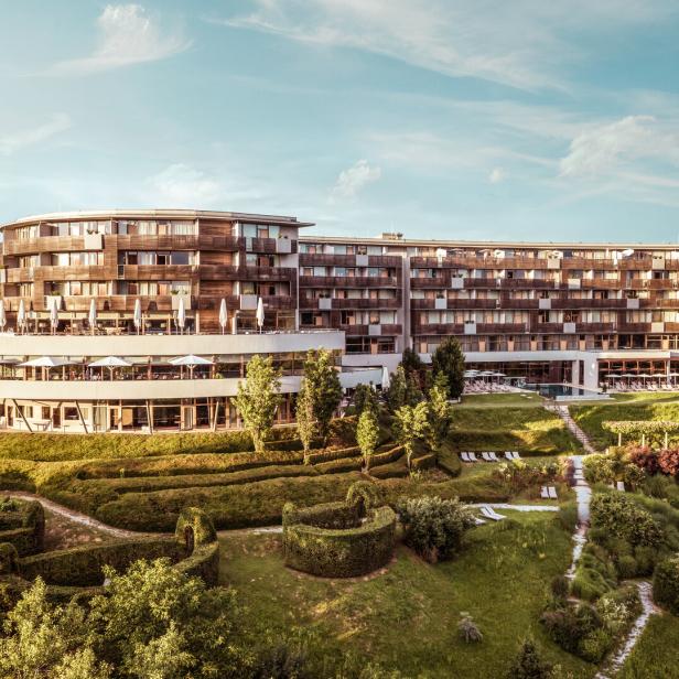 Ein großes Hotelgebäude mit einem gepflegten Garten im Grünen.