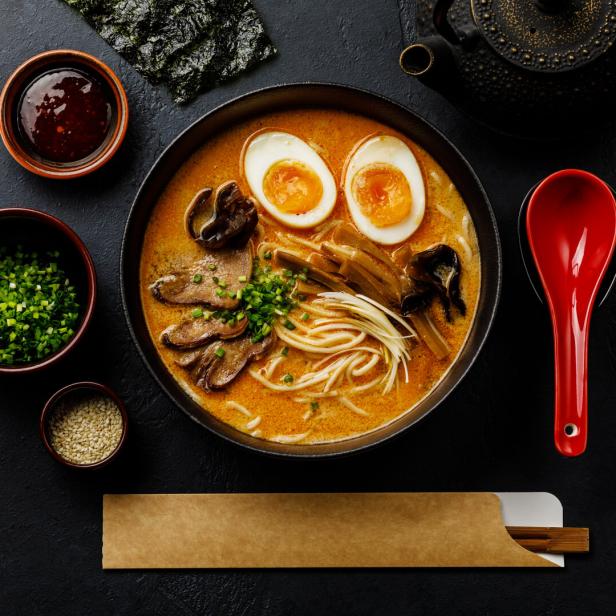 Ramen asian noodle in broth with Beef tongue meat, mushroom and Ajitama pickled egg in bowl on dark background
