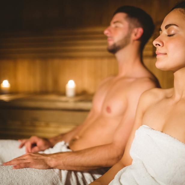 Ein Paar entspannt in einer Sauna mit gedämpftem Licht.