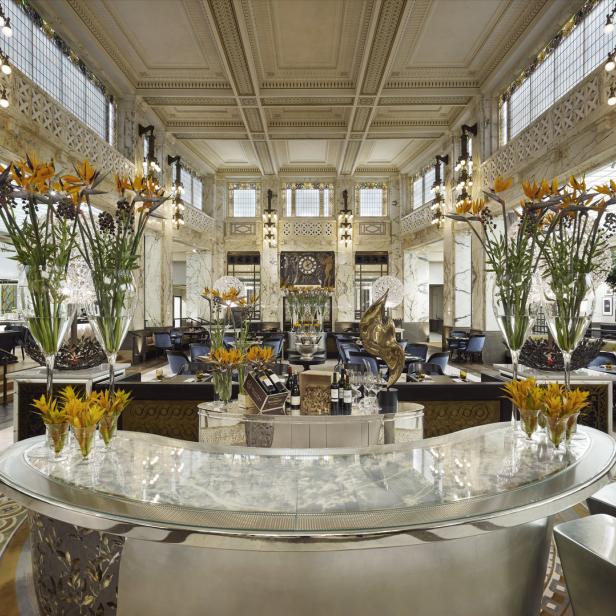 Innenansicht eines eleganten Restaurants mit Blumenarrangements und Marmorsäulen.