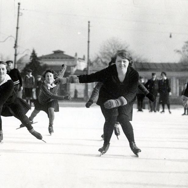Mehrere junge Frauen laufen auf einer Eisbahn Schlittschuh.