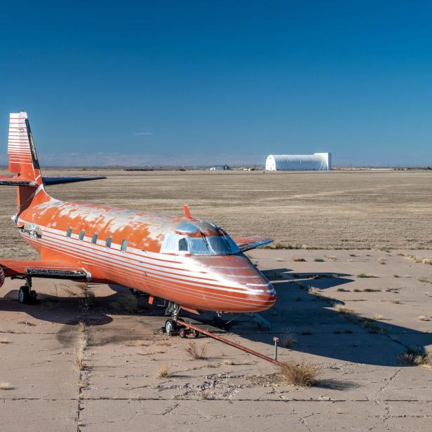 Ein verlassenes, orangefarbenes Flugzeug steht auf einem verlassenen Flugfeld.