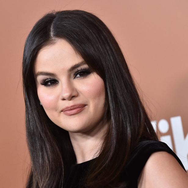 Selena Gomez posiert vor einem hellbraunen Hintergrund.