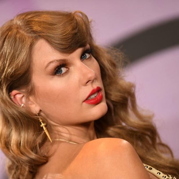 Nahaufnahme von Taylor Swift mit roten Lippen und goldenen Ohrringen.