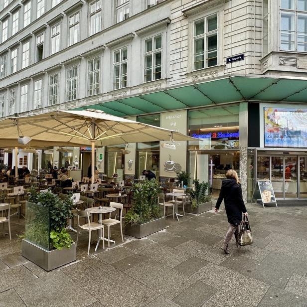 Ein Straßencafé in Wien mit Tischen und Stühlen im Freien.