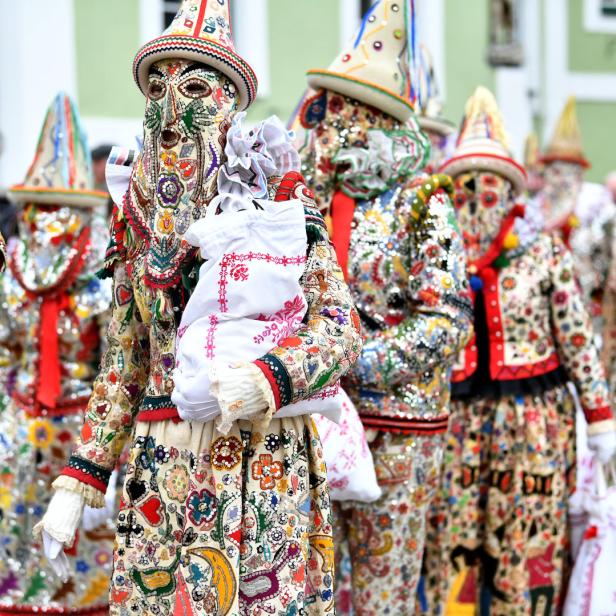 Eine Gruppe von Menschen in farbenfrohen, traditionellen Faschingskostümen und Masken.