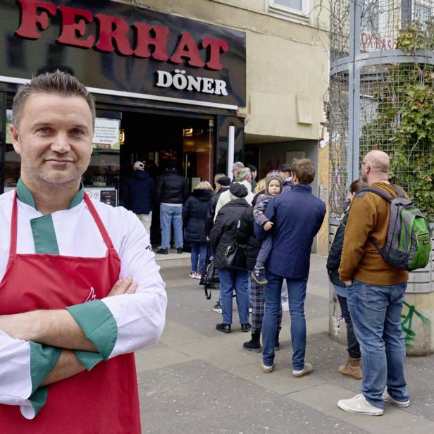 Ein Koch steht vor dem „Ferhat Döner“-Imbiss, vor dem eine Schlange wartet.