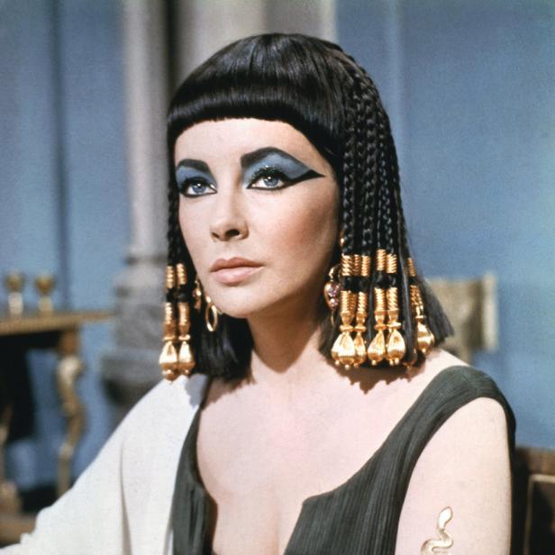 Elizabeth Taylor als Kleopatra mit starkem blauem Augen-Make-up und goldenem Armschmuck.