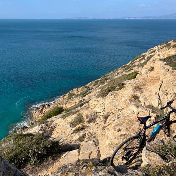 Ein Rennrad steht auf einem Felsen mit Blick auf das Meer.