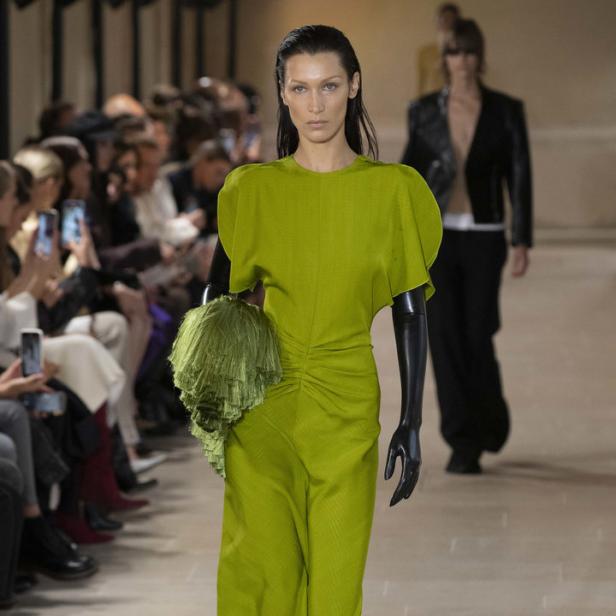 Bella Hadid präsentiert ein grünes Kleid und schwarze Handschuhe auf dem Laufsteg.