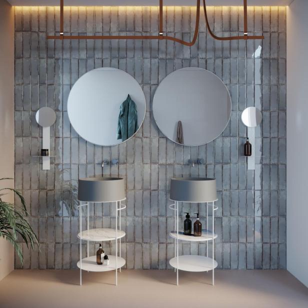 Ein Badezimmer mit zwei Waschbecken und runden Spiegeln vor einer grauen Wand.