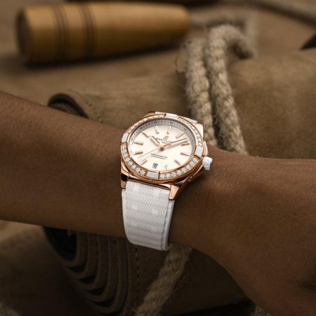 Eine goldene Breitling-Uhr mit Diamanten auf dem Handgelenk einer Person.