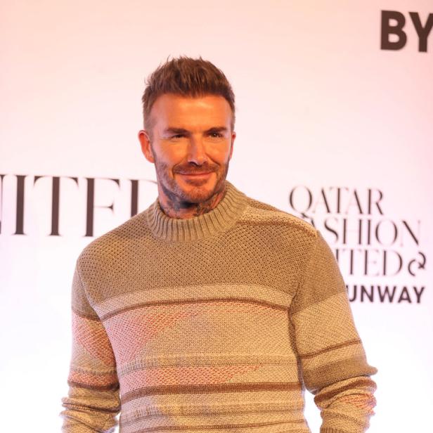 David Beckham trägt einen gestreiften Pullover und beigefarbene Hose.