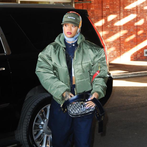 Rihanna verlässt ein Gebäude mit einer grünen Jacke, einer Supreme-Kappe und einer Dior-Tasche.