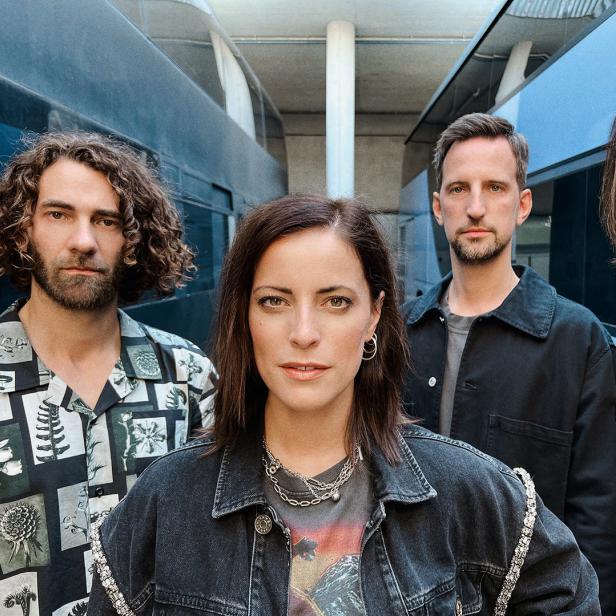Eine Band posiert vor einem modernen Gebäude für ein Foto.
