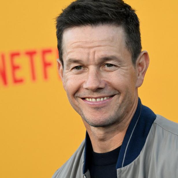 Mark Wahlberg lächelt vor einem gelben Netflix-Hintergrund.