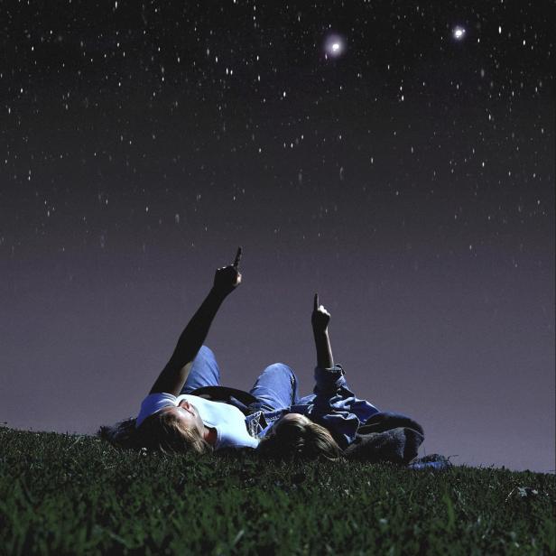 Mutter und Tochter liegen im Gras und schauen in den Sternenhimmel.