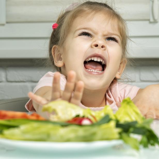 Ein kleines Mädchen weigert sich, Salat zu essen.