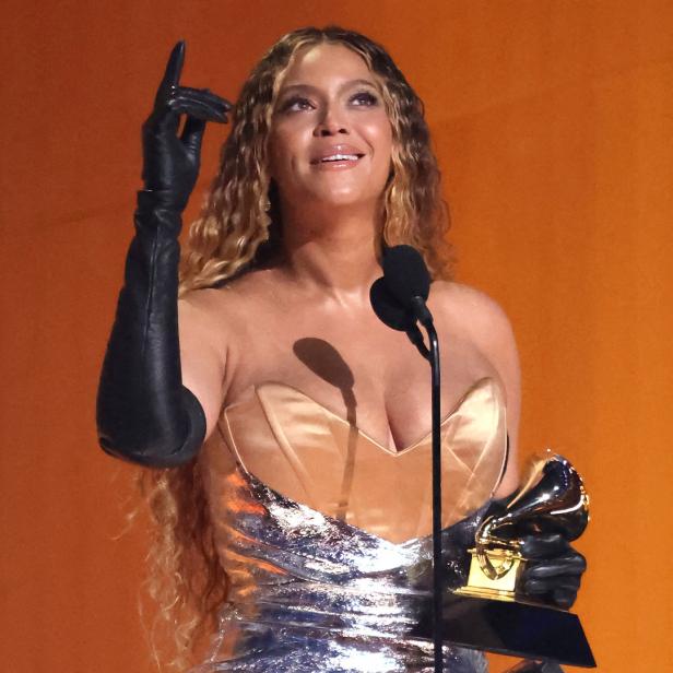 Beyoncé hält eine Grammy-Trophäe in der Hand und zeigt mit dem Finger nach oben.