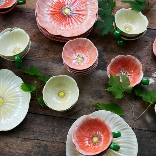 Teller und Schalen in Form von Mohnblumen liegen auf einem Holztisch.