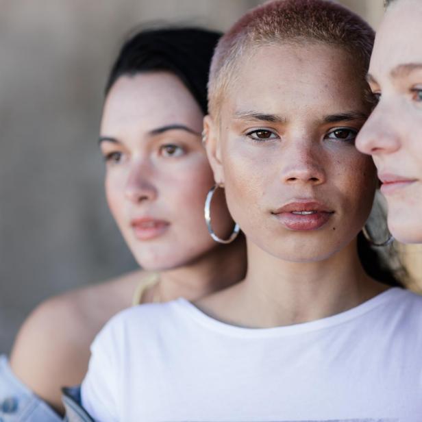 Drei junge, attraktive Frauen blicken in verschiedene Richtungen.