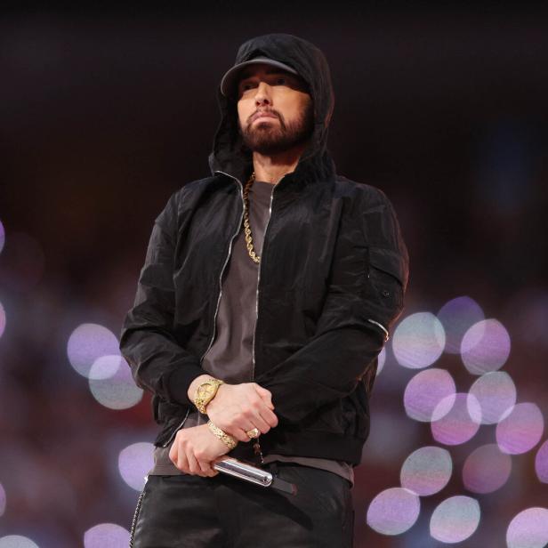 Eminem steht mit Kapuze und Mikrofon auf einer Bühne.