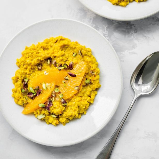 Karotten-Orangen-Porridge mit Pistazien auf zwei Tellern.