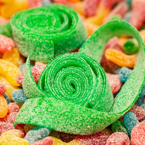 Nahaufnahme, Hintergrund mit grün gerollten Gummis, die mit Zucker überzogen sind.