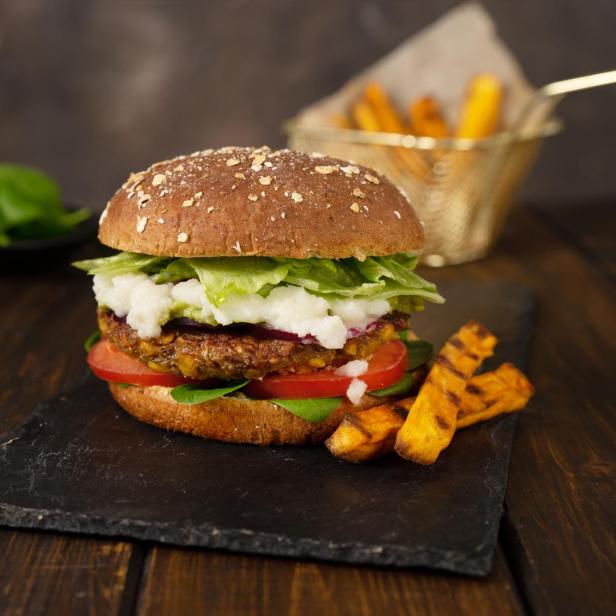 Köstliche frische hausgemachte vegane Linsen Burger auf einem rustikalen dunklen Hintergrund.