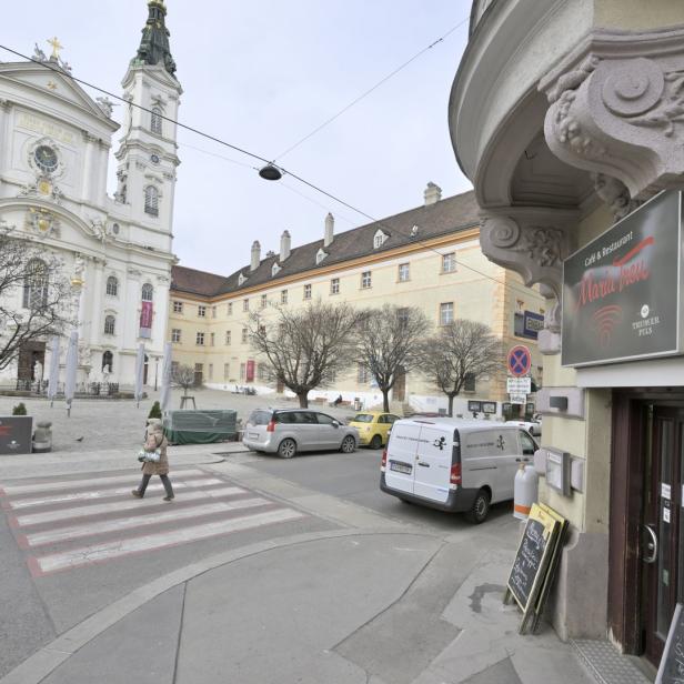 Eine Frau überquert einen Zebrastreifen vor der Stiftskirche Maria Treu in Wien.
