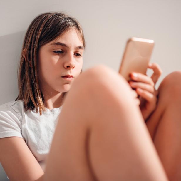 Ein Mädchen schaut ins Smartphone.