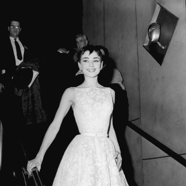 Audrey Hepburn in einem weißen Kleid auf einer Treppe.